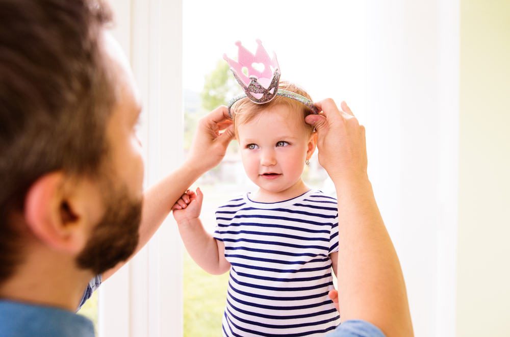 Hipster father with daughter putting crown on her head