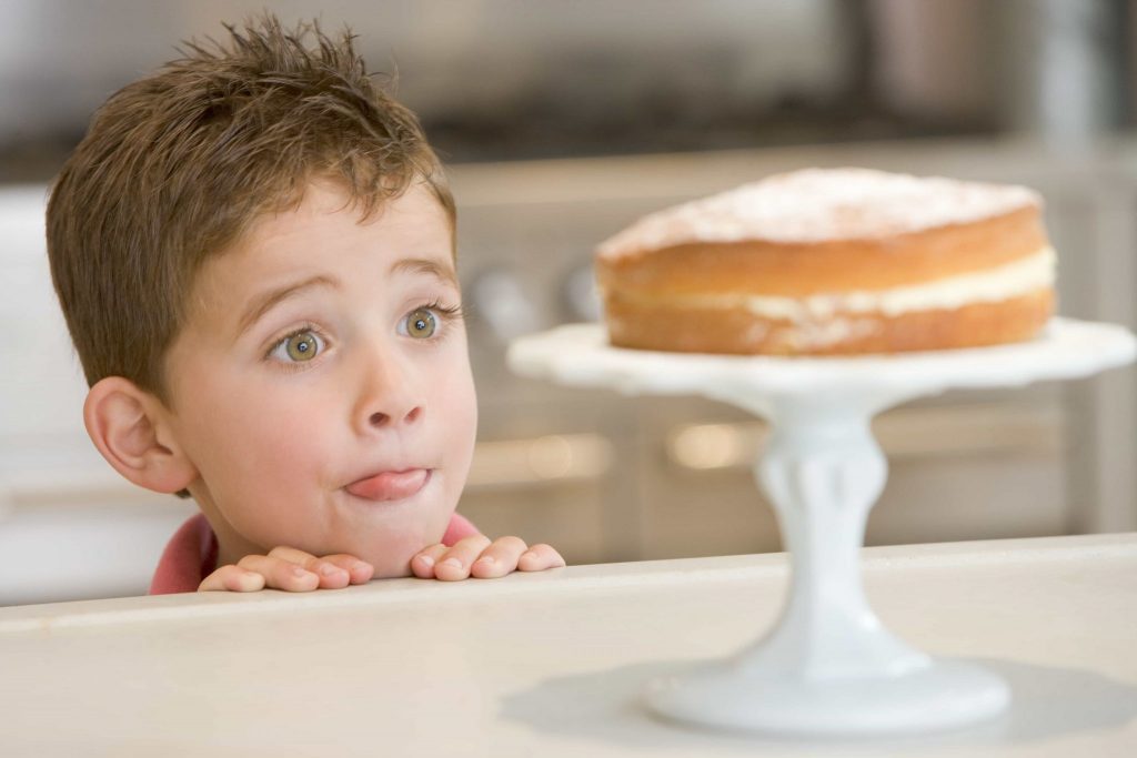 Boy staring longingly at cake at home licking lips