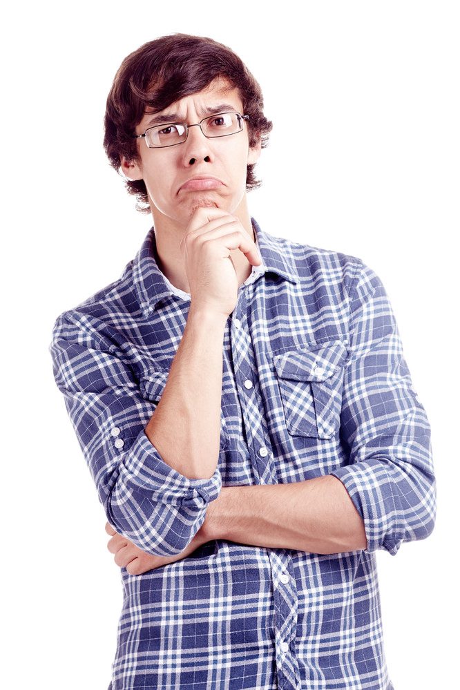 Young hispanic man wearing glasses and blue shirt with rolled up sleeves standing with hand on his chin and looking at camera with skeptical face expression isolated on white background