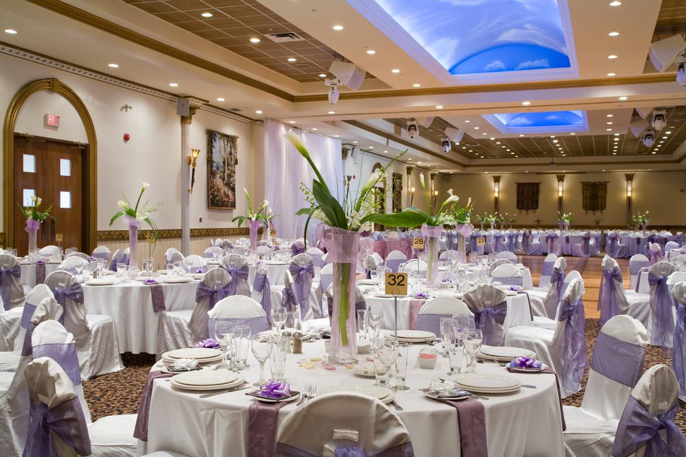 Indoor wedding reception hall with round tables and floral centerpieces