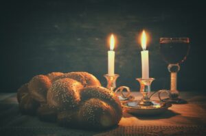Неброское изображение Шаббата. Халла, шаббатное вино и свечи на деревянном столе.
